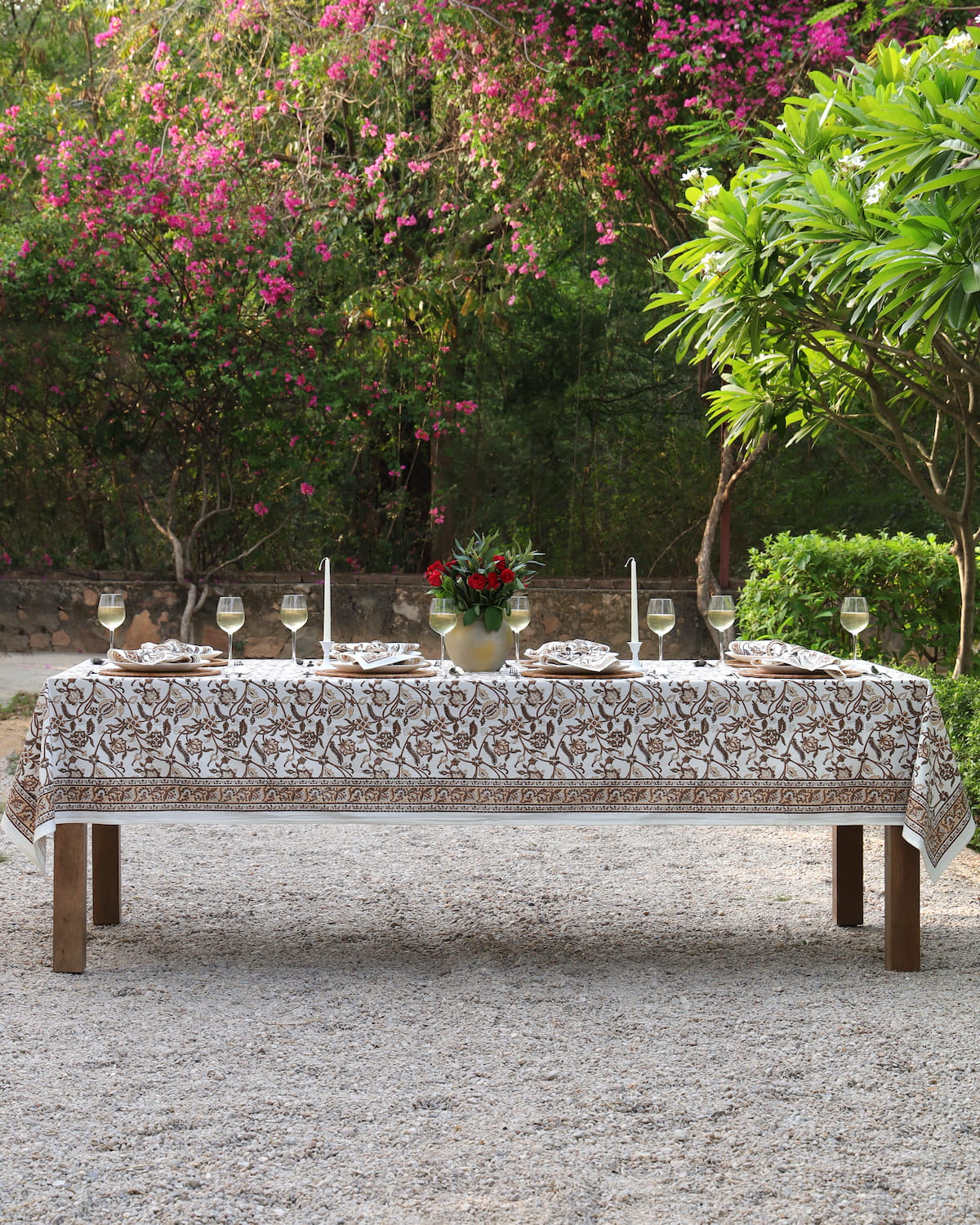 A garden table set for dinner with the Heirloom Chintz hand block printed cotton tablecloth in chestnut brown